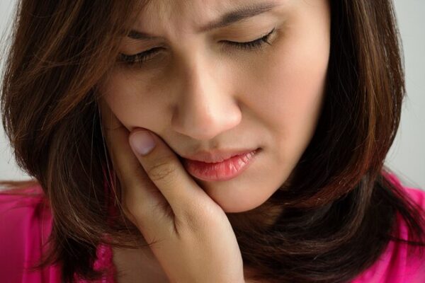 Temporomandibular joint diseases : Image showing woman holding her jaw in pain
