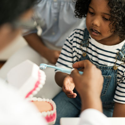 Dental Injuries in children : image showing an African child receiving tooth brushing instructions
