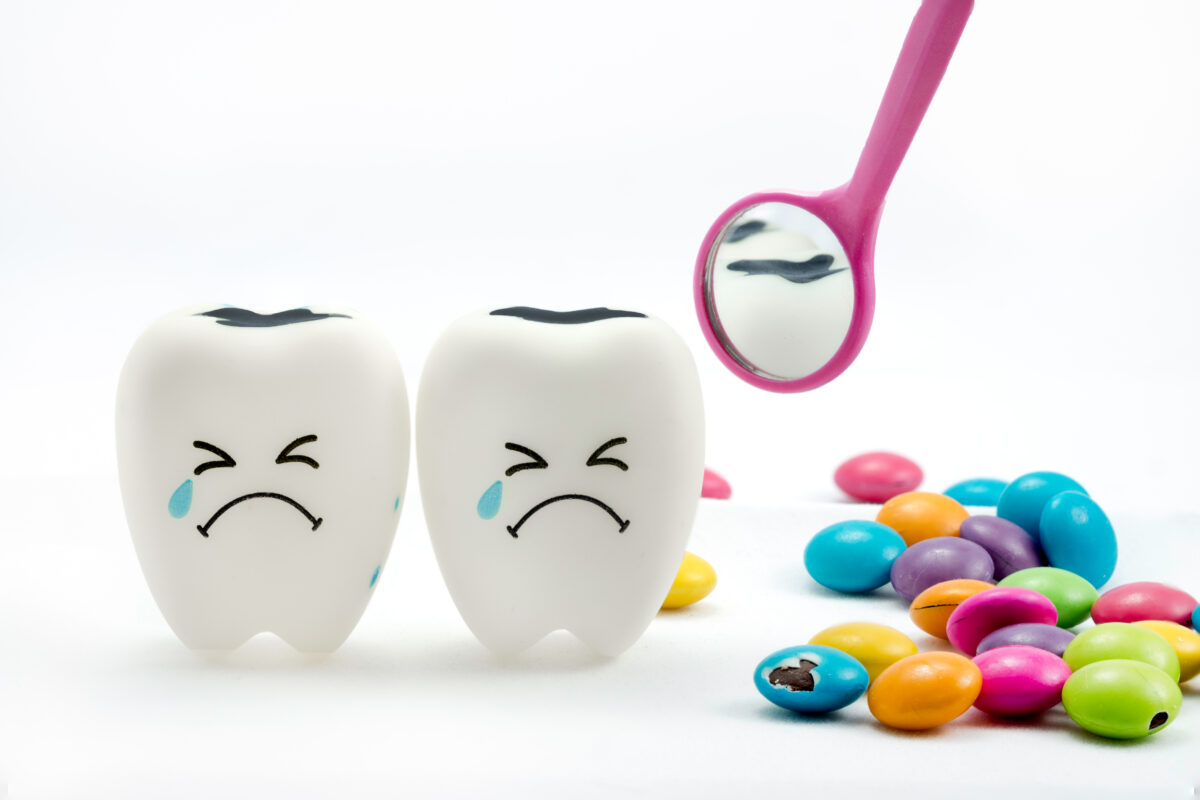 SWEET TOOTH : An illustration showing tooth decay with dental mirror and sugar coated chocolate on the side.