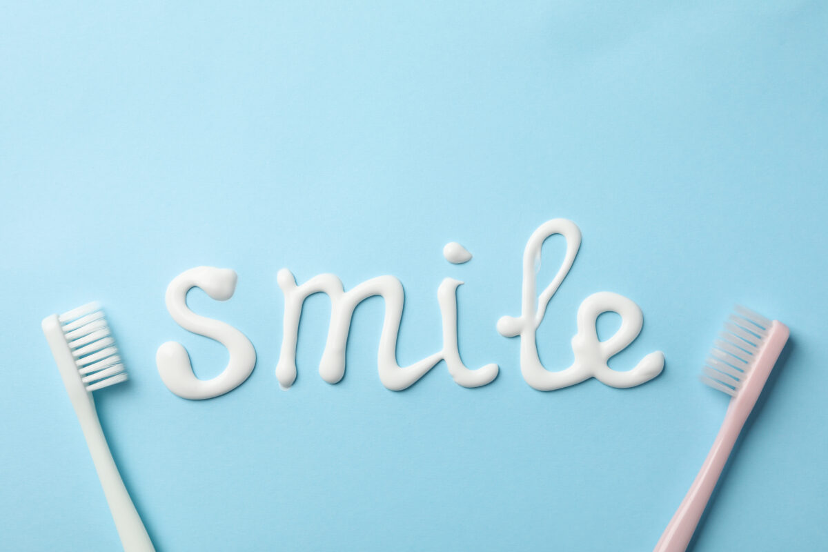 THE GOODNESS OF FLUORIDE : Word Smile made of toothpaste on blue background, top view